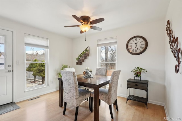 dining space featuring a healthy amount of sunlight, light wood-type flooring, visible vents, and baseboards