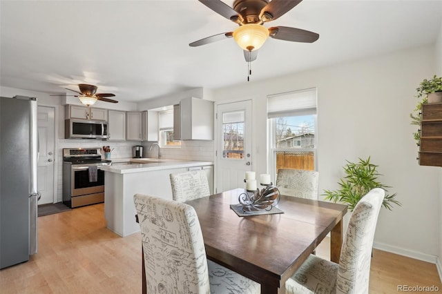 dining room with ceiling fan, light wood-style flooring, and baseboards