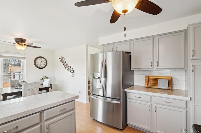 kitchen with backsplash, light wood-type flooring, stainless steel fridge, and gray cabinetry