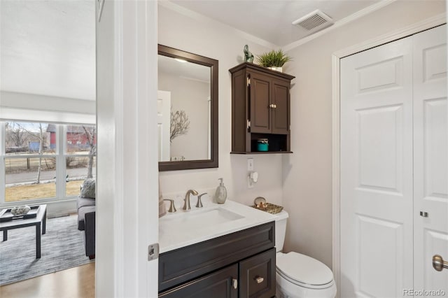 bathroom with toilet, vanity, visible vents, and crown molding