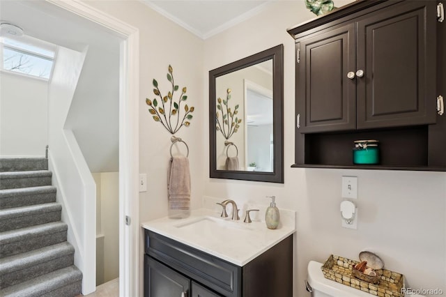 half bathroom with toilet, crown molding, and vanity