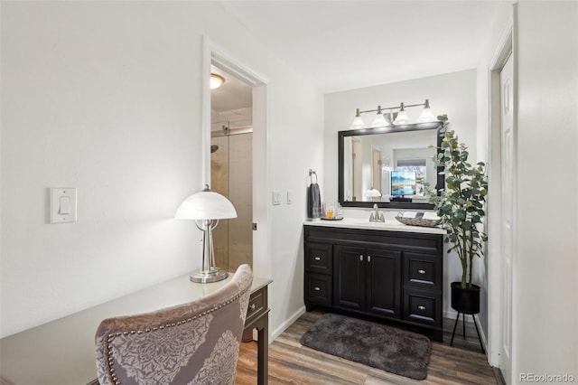 full bathroom with a shower with shower door, wood finished floors, and vanity