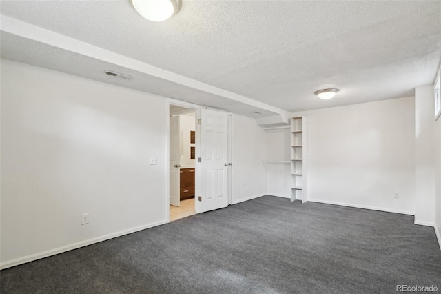 carpeted empty room with a textured ceiling, visible vents, and baseboards