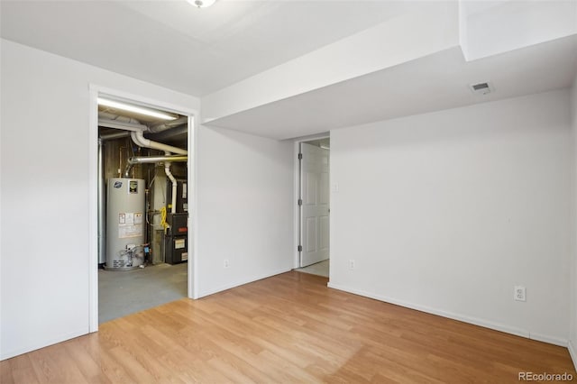 finished basement featuring gas water heater, wood finished floors, visible vents, and baseboards