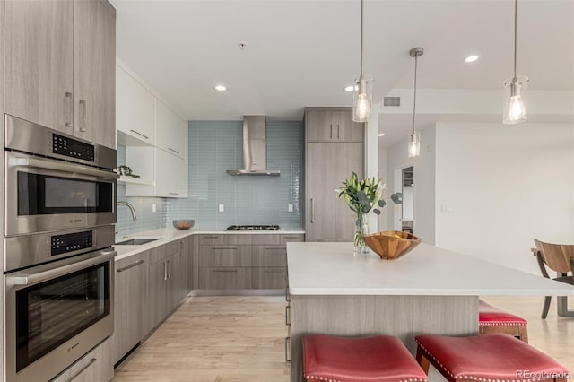 kitchen featuring wall chimney range hood, modern cabinets, and a sink