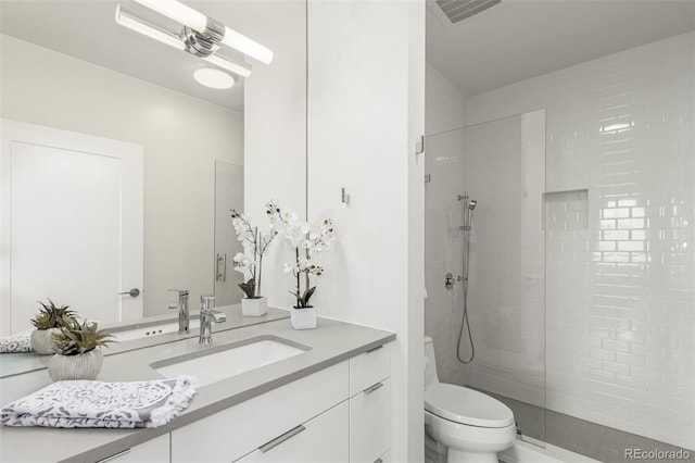 full bathroom with toilet, tiled shower, vanity, and visible vents