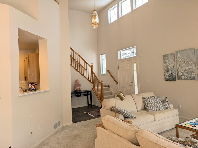 living room featuring a high ceiling, stairs, baseboards, and dark colored carpet