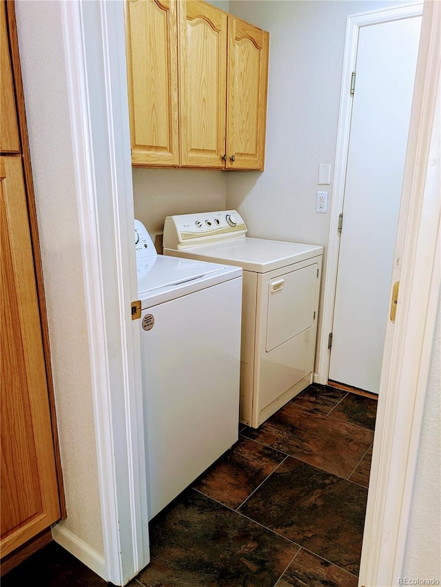 clothes washing area with stone finish floor, cabinet space, and washing machine and clothes dryer