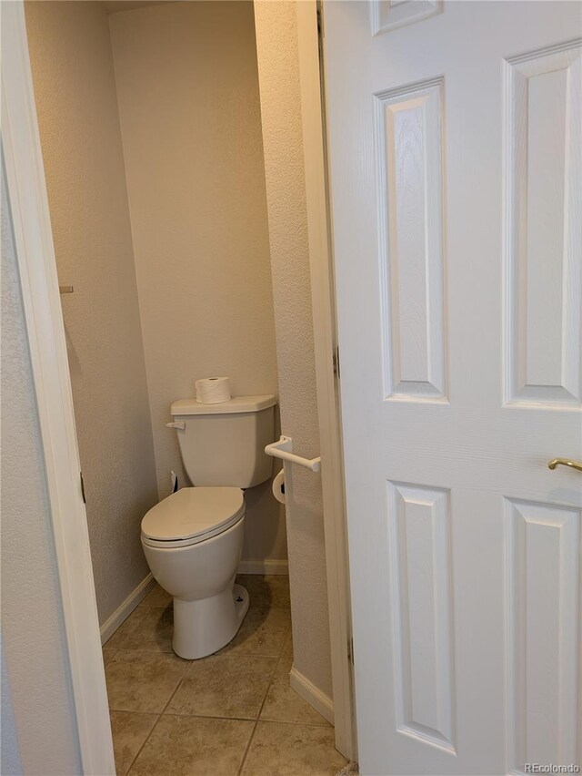 bathroom with toilet, baseboards, and tile patterned floors