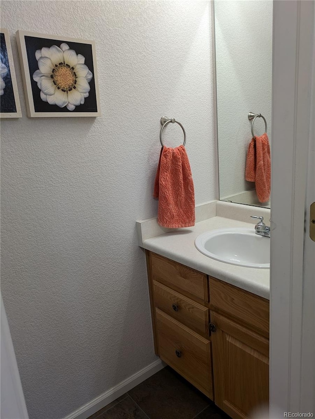 bathroom featuring a textured wall, tile patterned flooring, vanity, and baseboards