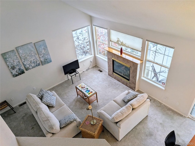 carpeted living room featuring a healthy amount of sunlight, baseboards, a premium fireplace, and visible vents