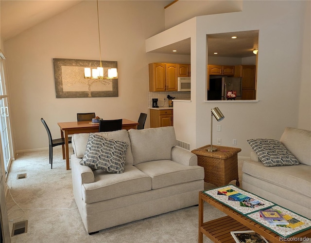 living room with a chandelier, light colored carpet, visible vents, and high vaulted ceiling