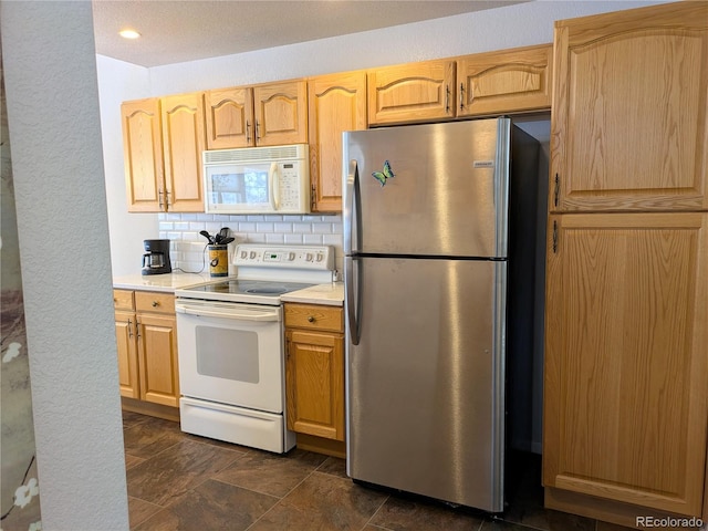 kitchen featuring light countertops, backsplash, stone finish flooring, light brown cabinets, and white appliances