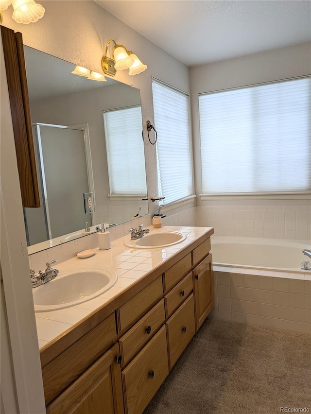 full bath with double vanity, a stall shower, a garden tub, and a sink