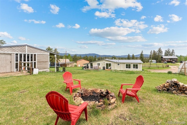 view of yard with a mountain view, an outdoor structure, and an outdoor fire pit