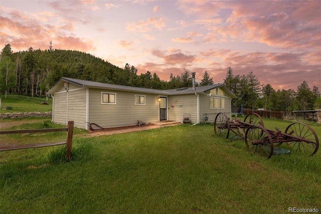 back house at dusk featuring a yard