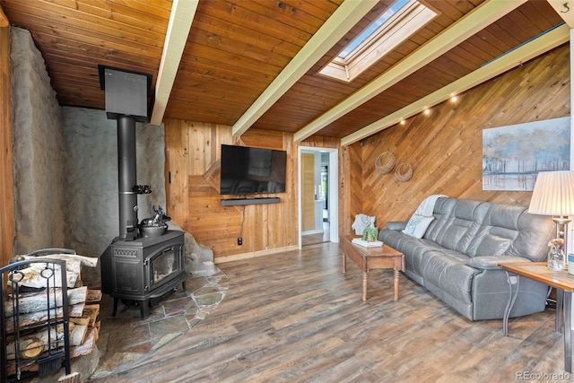 living room featuring beam ceiling, a skylight, a wood stove, wooden ceiling, and dark hardwood / wood-style floors