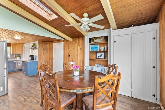 dining area featuring wood ceiling, vaulted ceiling with skylight, ceiling fan, light hardwood / wood-style floors, and wood walls