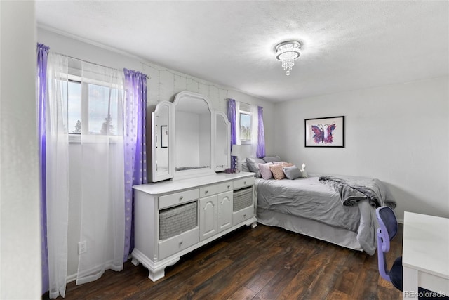 bedroom with a textured ceiling, dark wood-type flooring, and multiple windows