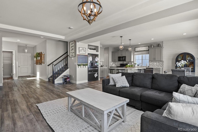 living area featuring dark wood-style flooring, recessed lighting, stairway, an inviting chandelier, and baseboards