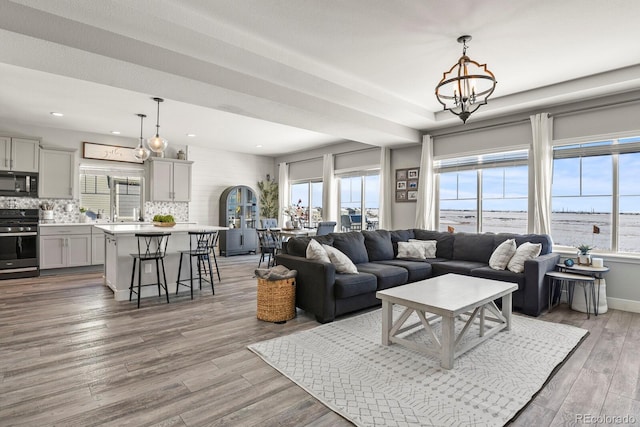 living room featuring light wood-style floors, recessed lighting, and a notable chandelier