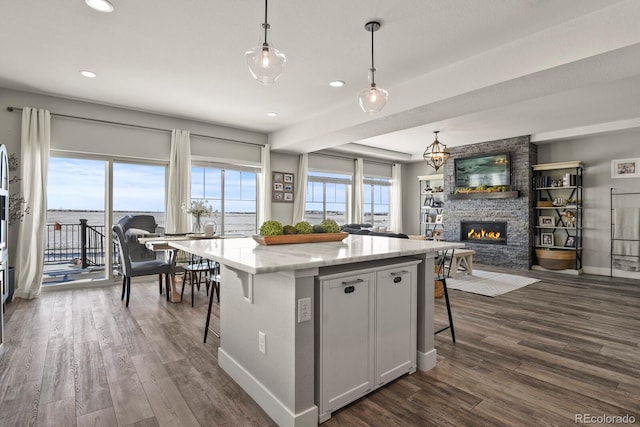 kitchen featuring white cabinets, a breakfast bar area, open floor plan, a center island, and hanging light fixtures