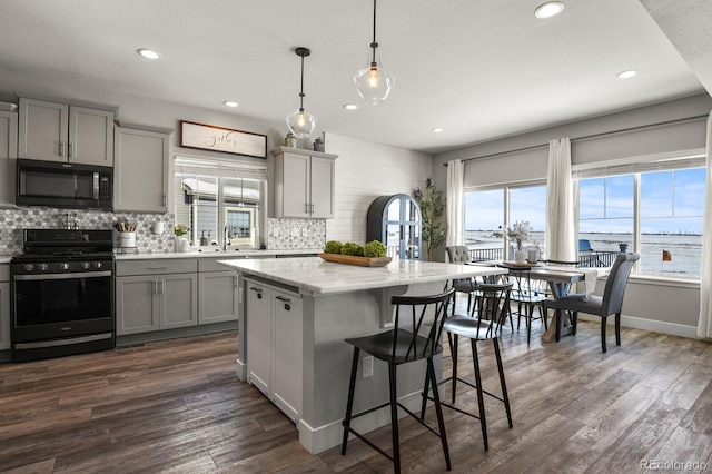 kitchen with black gas range, a center island, a water view, gray cabinetry, and pendant lighting