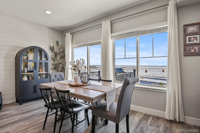 dining area featuring arched walkways, recessed lighting, wood finished floors, and baseboards