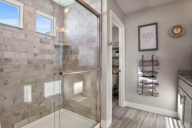 bathroom featuring baseboards, a shower stall, and toilet