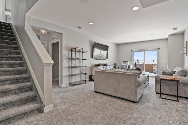 living area with baseboards, stairway, visible vents, and light colored carpet