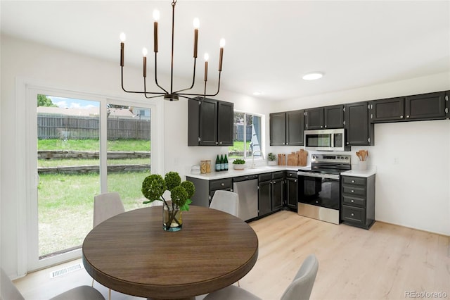 16322 E Idaho Pl, Aurora, CO 80017 - kitchen featuring appliances with stainless steel finishes, a chandelier, light countertops, light wood-style floors, and dark cabinetry