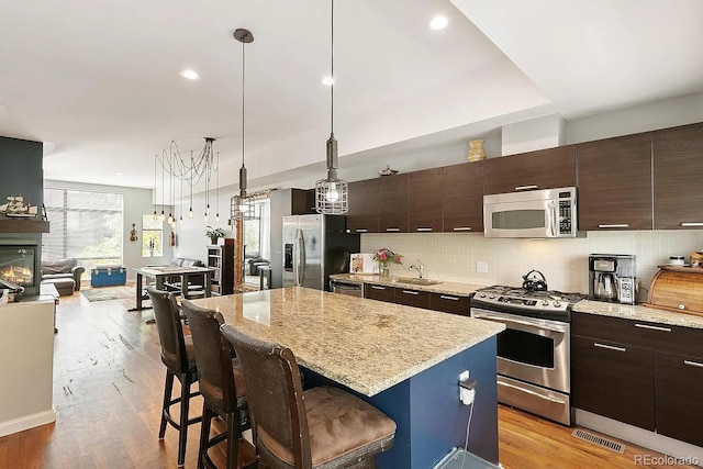 2335 Walnut St Unit 10, Denver, CO 80205 - kitchen featuring appliances with stainless steel finishes, a breakfast bar area, a kitchen island, dark brown cabinetry, and recessed lighting