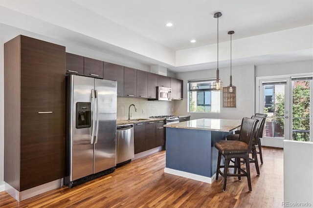 2335 Walnut St Unit 10, Denver, CO 80205 - kitchen with stainless steel appliances, a center island, wood finished floors, a kitchen breakfast bar, and recessed lighting