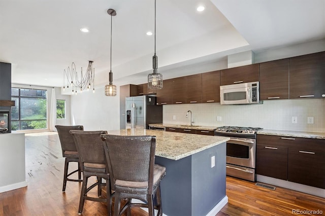 2335 Walnut St Unit 10, Denver, CO 80205 - kitchen featuring stainless steel appliances, a breakfast bar, a kitchen island, decorative backsplash, and recessed lighting