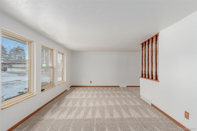 carpeted spare room with a textured ceiling