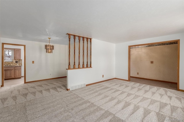 empty room featuring light carpet and a chandelier