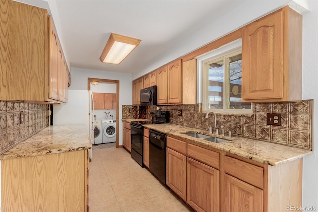 kitchen with light stone countertops, sink, separate washer and dryer, light tile patterned floors, and black appliances