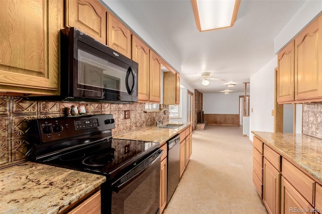 kitchen with backsplash, black appliances, sink, light stone countertops, and light brown cabinetry