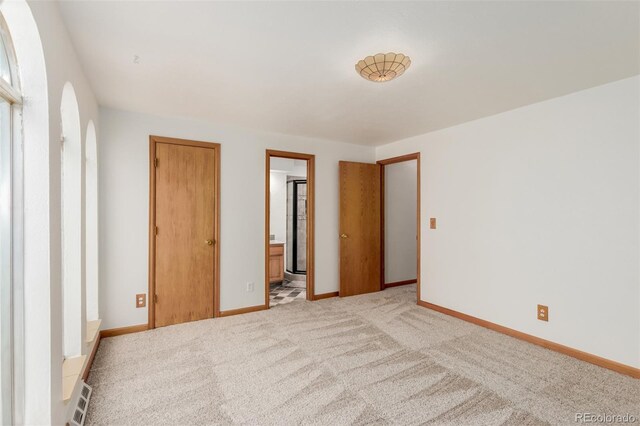 unfurnished bedroom featuring ensuite bathroom and light colored carpet