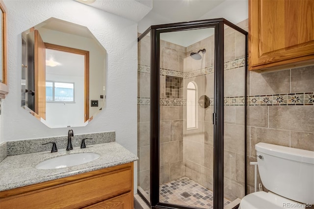 bathroom featuring vanity, toilet, and a shower with door