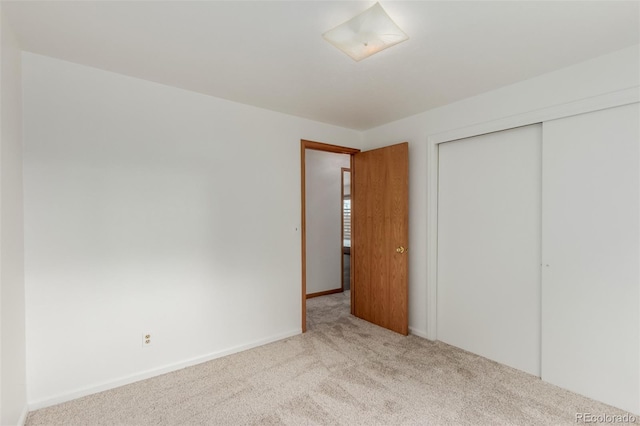 unfurnished bedroom featuring light carpet and a closet