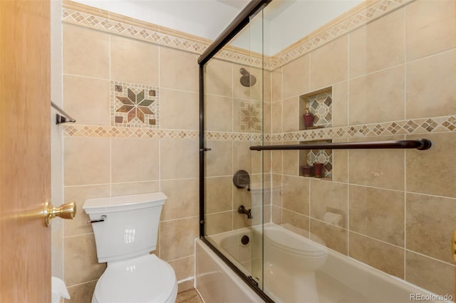 bathroom featuring toilet, combined bath / shower with glass door, and tile walls