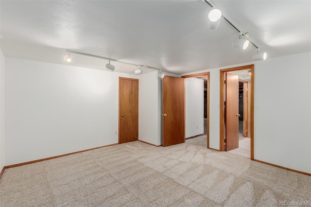 unfurnished room featuring rail lighting and light colored carpet