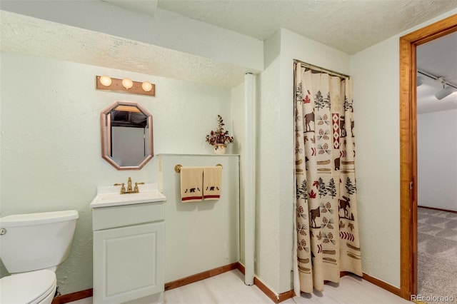 bathroom featuring vanity, a textured ceiling, rail lighting, and toilet