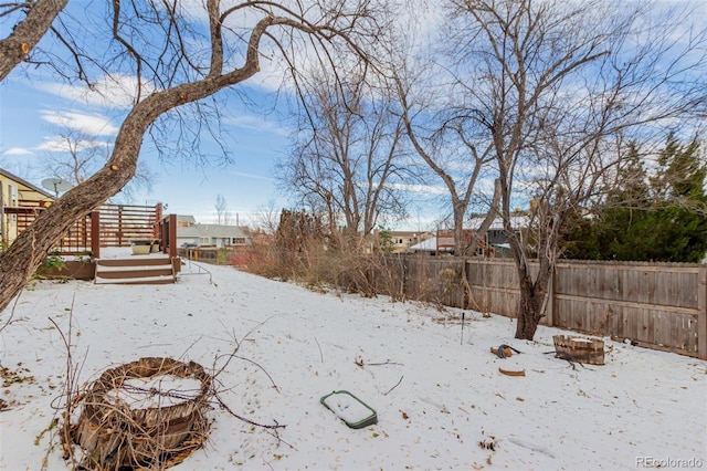 snowy yard with a fire pit and a deck