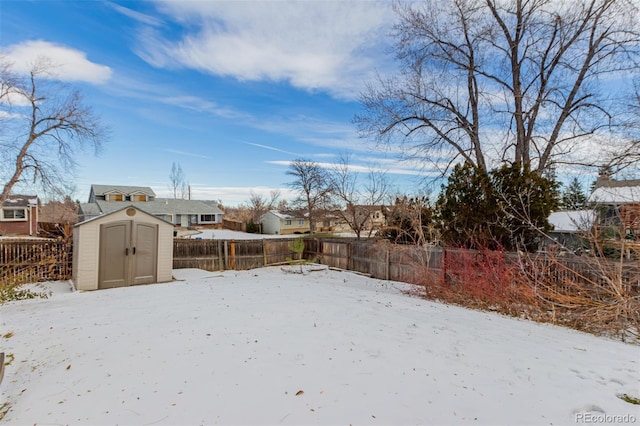 snowy yard featuring a storage unit