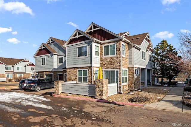 view of front of house featuring stone siding, a residential view, and board and batten siding