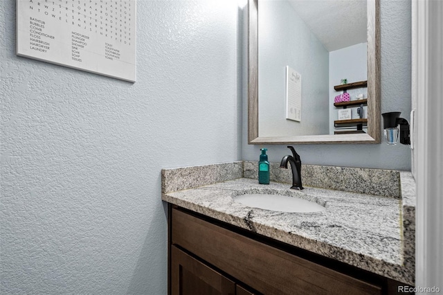 bathroom featuring a textured wall and vanity