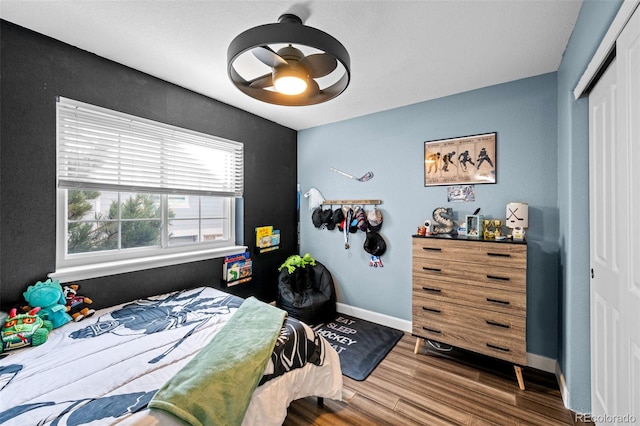 bedroom with a closet, ceiling fan, baseboards, and wood finished floors