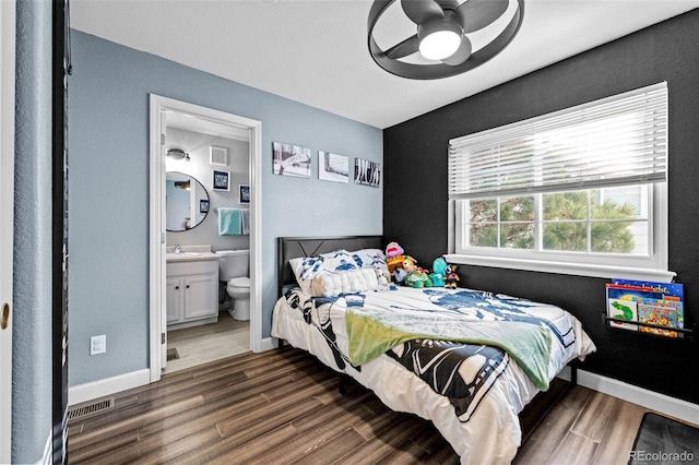 bedroom featuring ensuite bathroom, dark wood-style flooring, visible vents, and baseboards